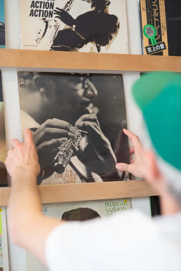 disquaire qui réorganise les disques au mur de sa boutique de disques